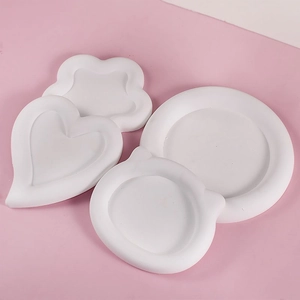 Detailed view of four assorted white plaster coaster trays in cat and heart shapes