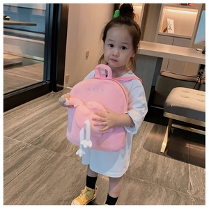 Pink plush kids backpack with a cute white swan and embroidery held by a small child