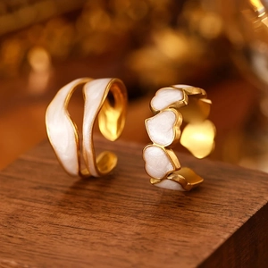 Close-up of gold stainless steel rings with white enamel heart and wavy designs