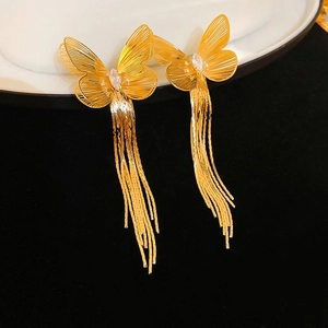 Gros plan de boucles d'oreilles papillon dorées évidées avec de longues franges et zircon