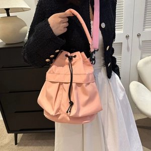 Détail d'un sac seau en nylon rose avec cordon noir et bandoulière large ajustable