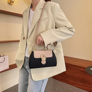 Detailed close-up of a two-tone leather handbag with gold buckle on a stylish model