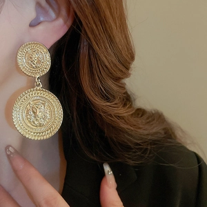 Macro detail of vintage gold lion head earrings with ornate double disc design on ear lobe