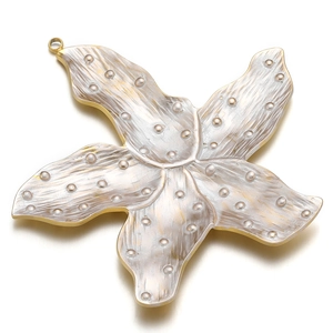 Detailed macro view of a gold-plated starfish pendant with white enamel and golden dots