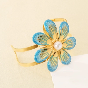 Macro view of gold flower bangle featuring blue gradient enamel and center pearl detail