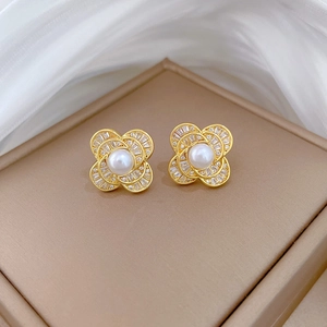 Elegant gold flower stud earrings with white pearl and sparkling crystals on beige jewelry box