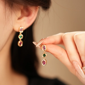 Detail von Vintage-Goldohrringen mit ovalen lila, grünen und rosa Edelsteinen