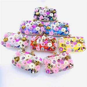 Detail showing various colors of handmade floral beaded evening clutch bags with 3D petals