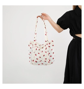 Detailed texture of off-white corduroy tote bag featuring red strawberry floral patterns