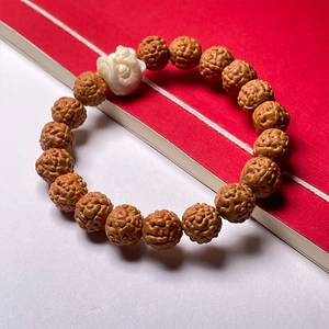 Rudraksha seed bracelet with white lion head bead on a red and white background