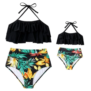 Matching parent-child bikini set featuring black ruffle tops and tropical print bottoms
