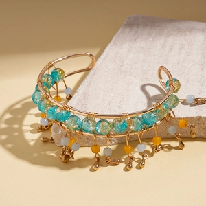 Detail of bohemian gold wire cuff bracelet with blue beads and hanging charms