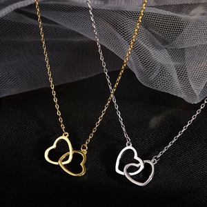 Elegant gold and silver interlocking heart necklace on textured background