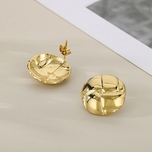 Golden round stud earrings featuring classic quilted texture on a beige background