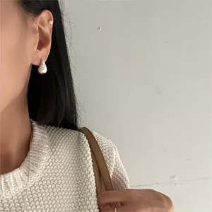 Close-up of minimalist water drop silver earrings worn by a model for a stylish look