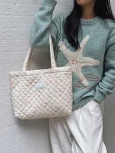 Close-up of quilted tote bag with colorful mini bows and transparent brand logo