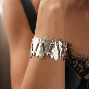 Détail d'un bracelet en métal argenté avec cœurs texturés de style vintage et élastique
