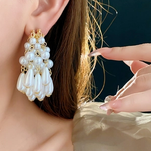 Detail of elegant gold drop earrings with tiered white pearls and tassel design
