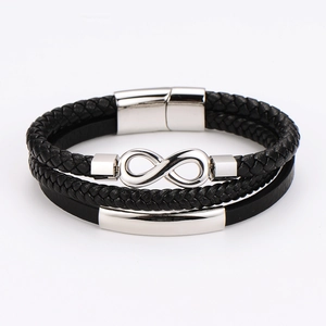 Détail d'un bracelet multicouche en cuir tressé noir avec symbole infini en argent et barre métal