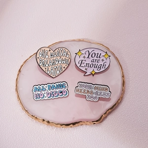 Set of four metal enamel mental health badges on a decorative pink agate slice