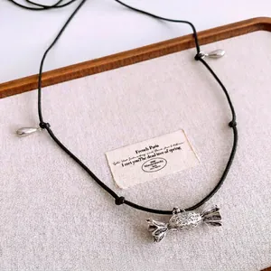 Vintage silver candy pendant necklace with black cord on rustic display tray