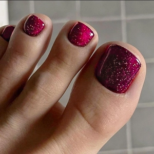 Close-up of red glitter press-on toenails with a sparkling finish for a summer pedicure