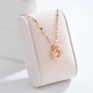Close-up of rose gold swan pendant with sparkling cubic zirconia on a beige stand