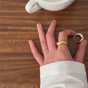 Detail showing matte gold wave ring and silver polished band on wooden table