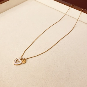 Détail du collier plaqué or avec pendentifs cœur évidé et smiley sur présentoir