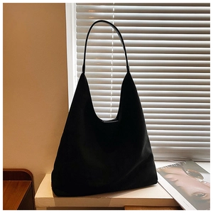 Detail of minimalist black suede tote bag with smooth texture and sleek shoulder strap