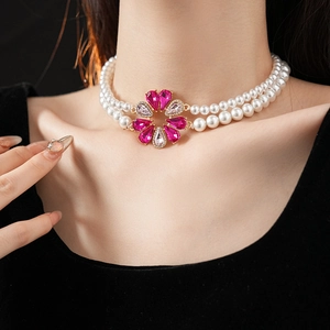 Dettaglio della collana di perle a strati con ciondolo a fiore di strass su una modella
