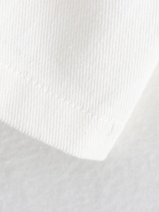 Macro detail showing high-quality stitching and twill texture on white fabric top
