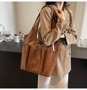 Brown vintage faux leather tote bag with exterior pocket shown in a cozy cafe setting