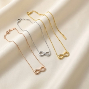 Three infinity necklaces in gold, silver, and rose gold with diamond accents