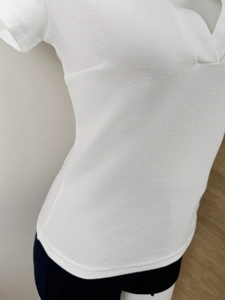 Close-up of white short-sleeve polo shirt showing V-neck design and knit fabric texture