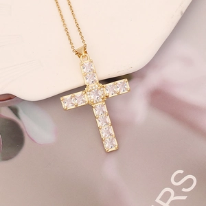 Macro shot of gold cross necklace featuring baguette-cut cubic zirconia inlays