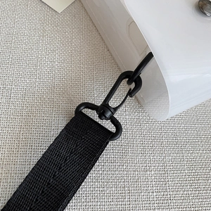 Dettaglio della fibbia rotante e della tracolla in nylon nero su una borsa trasparente