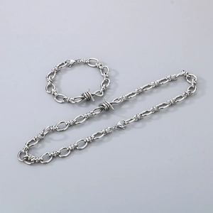 Flat lay of punk barbed wire style necklace and bracelet set in polished silver metal