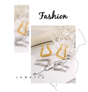 Macro detail of gold and silver twisted geometric triangular earrings on a white background