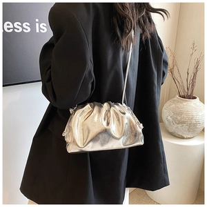 Detailed view of silver pleated dumpling bag on a model wearing a black blazer