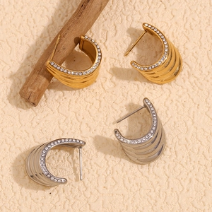 Gold and silver wavy layered earrings with micro-inlaid crystals on textured background