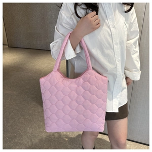 Detailed view of pink quilted tote bag with wavy stitching and soft puffer texture