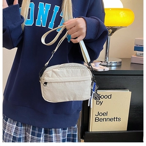 Détail d'un petit sac bandoulière en nylon crème avec sangle réglable et décoration