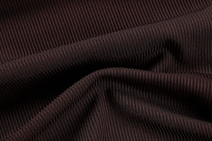 Detailed macro view of dark brown ribbed knit fabric with vertical texture and soft shadows