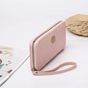 Detail of pink long wallet with quilted pattern, gold hardware and a wristlet strap
