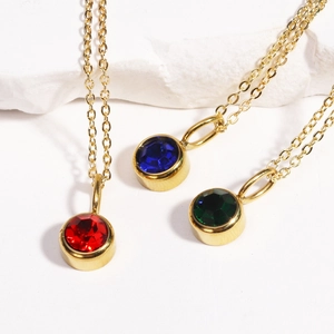 Three gold birthstone necklaces with red, blue and green round crystal pendants