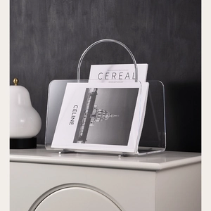 Detail of transparent acrylic magazine rack with silver metal handle on a side cabinet