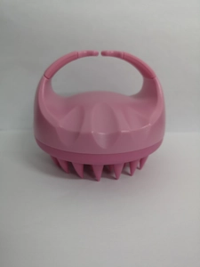 Close-up of pink silicone scalp massager brush with ergonomic handle and soft bristles