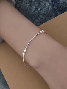Macro detail of a minimalist S925 silver bracelet with small beads on a woman's wrist