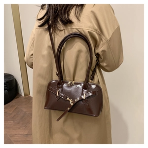 Detail showing deep brown glossy leather bag on model with adjustable strap